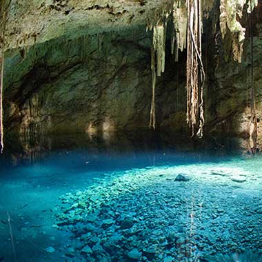 Ein türkisfarbenes Wasserbecken glänzt in einer Höhle. Die Farbe wird durch fein verteilte Mineralien verursacht, die im Wasser suspendiert sind.